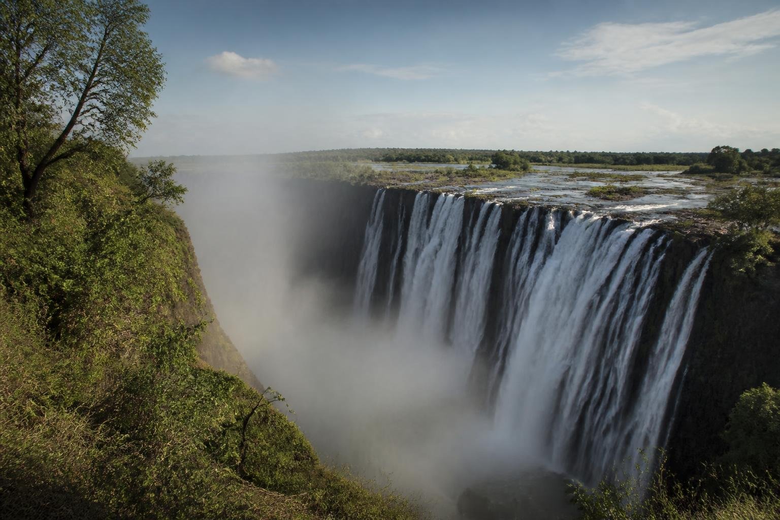 Vue panoramique des Chutes Victoria depuis un belvédère avec la brume de l’eau